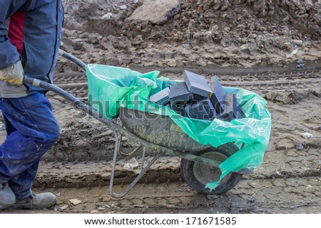 constuction worker with bricks in wheelbarrow at a building site