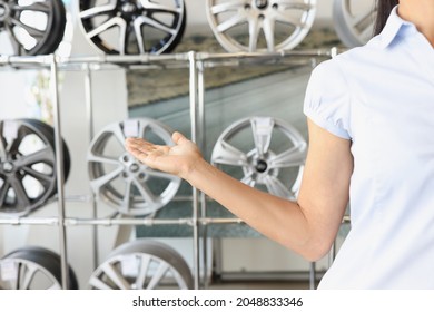 Consultant Manager Points To Exhibition Stand Of New Modern Car Rims.