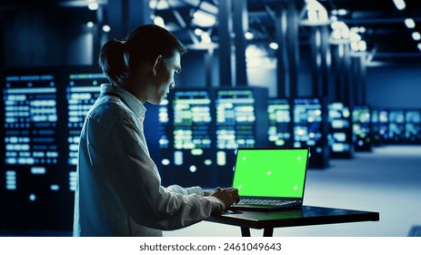 IT consultant running code on chroma key laptop, troubleshooting data center equipment. Cloud computing business executive using green screen device to examine servers and networking systems