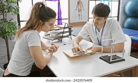 Consultation between a male therapist and a female patient in a physiotherapy clinic indoors. - Powered by Shutterstock