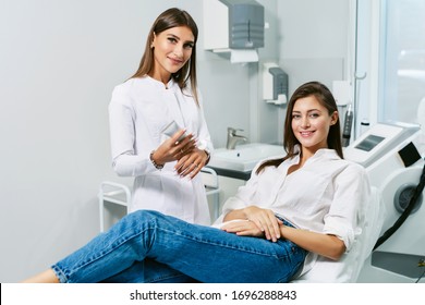 Consultation In Cosmetology Clinic. Female Beauty Doctor Talking With Patient. A Young Girl Tells What She Wants Change In Her Face. Client Shows On Himself Using Mirror. Doctor Listening Carefully