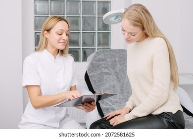 Consultation In Cosmetology Clinic. Female Professional Beauty Doctor Talking With Pretty Young Female.