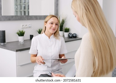 Consultation In Cosmetology Clinic. Female Professional Beauty Doctor Talking With Pretty Young Female.