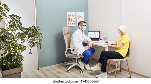 Consultation with experienced male audiologist wearing protective mask for an elderly patient at hearing clinic