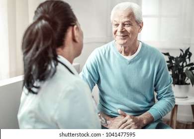 Consulting conversation. Senior gray hair pleasant man sitting in the room and looking at the doctor and smiling. - Powered by Shutterstock