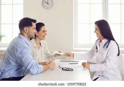 Consulting family doctor at clinic. Happy patients take therapy prescription that general practitioner gives. Future parents get good health exam result. Infertile married couple have success with IVF