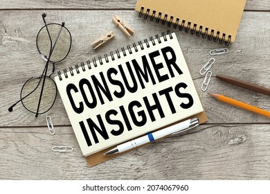 Consumer Insights. Text On White Paper. The Inscription On The Notebook. Business Concept. Notepad On A Wooden Background. Glasses, Pen, Pencil