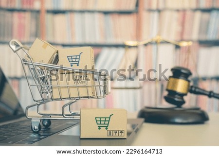 Consumer rights and consumer protection, business law concept : Shopping basket, shopping boxes and a shopping cart on a laptop computer with judge gavel, balance sale of justice and bookshelf behind.