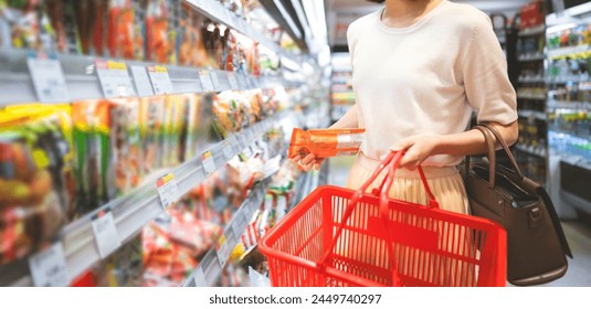 Consumer shopping at supermarket concept. Young adult asian woman customer choosing instant asia food product from shelf. Consumer buying at grocery store lifestyles. - Powered by Shutterstock