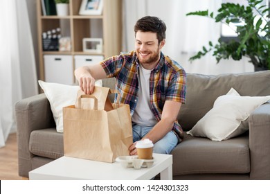 Consumption, Eating And People Concept - Smiling Man Unpacking Takeaway Food At Home