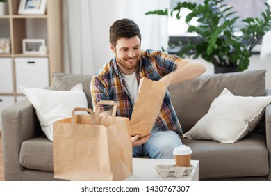 Consumption, Eating And People Concept - Smiling Man Unpacking Takeaway Food At Home