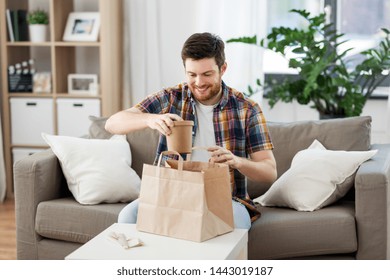 Consumption, Eating And People Concept - Smiling Man Unpacking Takeaway Food At Home