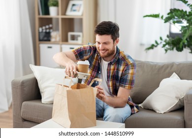 Consumption, Eating And People Concept - Smiling Man Unpacking Takeaway Food At Home