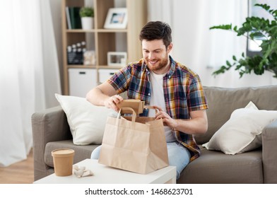 Consumption, Eating And People Concept - Smiling Man Unpacking Takeaway Food At Home