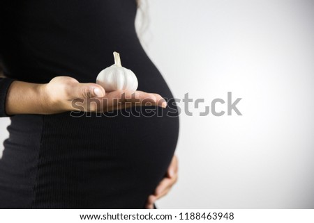 The consumption of garlic during pregnancy. Healthy food and people concept. Pregnant woman eat garlic.