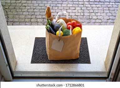 Contacless food delivery service concept. Paper bag with groceries delivered and left oudside at entrance door. View from inside through open door.  Online shopping. 