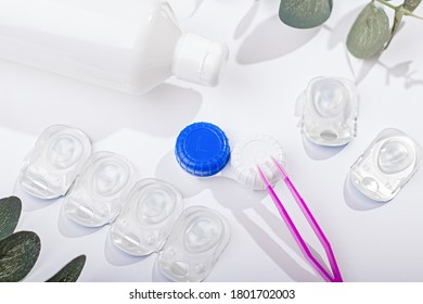 Contact Lens Kit With Lenses, Bottle Of Lens Solution, Case, Tweezers On White Table, Top View