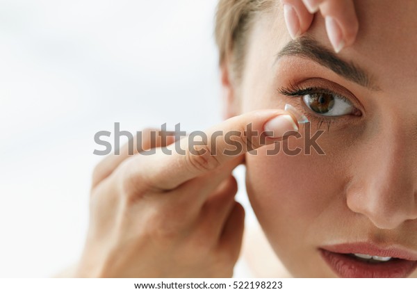 Contact Lens For Vision. Closeup Of Female Face With\
Applying Contact Lens On Her Brown Eyes. Beautiful Woman Putting\
Eye Lenses With Hands. Opthalmology Medicine And Health. High\
Resolution 