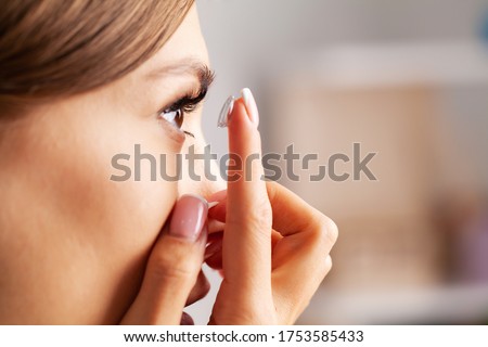 Contact Lens For Vision. Young woman puts on optical lenses at home in the room