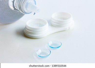Contact lenses, case and bottle with solution on white background. Eye health and care, eyesight and vision, ophthalmology and optometry concept, close up, selective focus