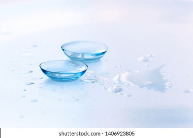 Contact lenses and water drops on light blue background. Eyewear, eyesight and vision, eye care and health, ophthalmology and optometry concept, close up, selective focus