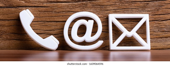 Contact Methods. Close-up Of A Phone, Email And Post Icons Leaning On Wooden Wall