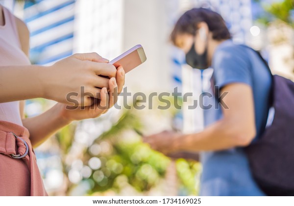 contact tracing app COVID-19 Pandemic\
Coronavirus Mobile Application - people Wearing Face Mask Using\
Smart Phone App in City Street to Aid Contact Tracing in Response\
to the 2019-20\
Coronavirus