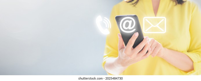 contact us. Close up of women's hands holding cellphone smartphone. Woman holding cell phone with with mail, phone, email icon. cutomer support concept. copy space. blue background. Indoor. copy space