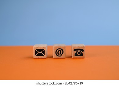Contact us concept with mail, e-mail, and phone icons on wooden blocks. Contact methods. Orange and blue backgrounds.  - Shutterstock ID 2042796719