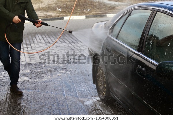 Contactless car wash self-service. Young man\
washing his car\
spring.