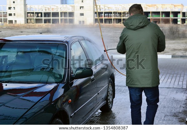 Contactless car wash self-service. Young man
washing his car
spring.