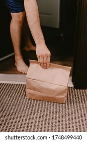 Contactless Food Delivery From Restaurant. New Normal. Coronavirus Covid-19 Reality. Order Dinner Online. No Dining In. Quarantine Life. Recycle Paper Bag. Chinese Meal. Man Holds Bag Apartment Door.