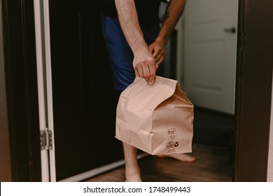 Contactless Food Delivery From Restaurant. New Normal. Coronavirus Covid-19 Reality. Order Dinner Online. No Dining In. Quarantine Life. Recycle Paper Bag. Chinese Meal. Man Holds Bag Apartment Door.