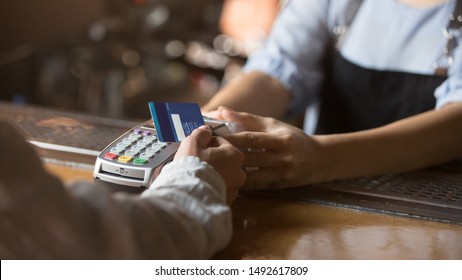 Contactless payment concept, female customer holding credit card near nfc technology on counter, client make transaction pay bill on terminal rfid cashier machine in restaurant store, close up view - Shutterstock ID 1492617809