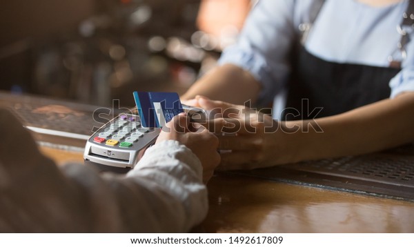 Contactless payment concept, female customer holding\
credit card near nfc technology on counter, client make transaction\
pay bill on terminal rfid cashier machine in restaurant store,\
close up view