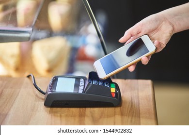 Contactless payment method. The girl applies the phone to the banking terminal. Female customers using the cell phone to pay for goods.