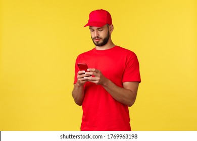 Contactless payment, online delivery, internet shopping and parcel tracking concept. Young courier looking at map mobile phone to find client address. Employee using smartphone, yellow background - Powered by Shutterstock