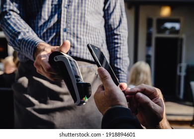 Contactless Payment System, Close-up. Client Man Paying Bill By Phone In Outside Restaurant, Bar Or Cafe.