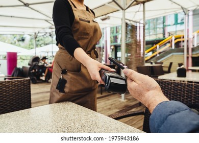 Contactless Payment System, Close-up. Client Man Paying Bill By Smartphone In Outside Restaurant, Bar Or Cafe.