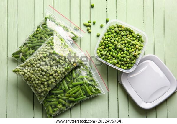 Container and bags with frozen vegetables on\
color wooden\
background