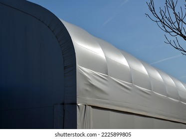 container building permanently forms a warehouse with offices. covered with a rubber sheet on tent structure. ventilation with help of a stainless steel propeller chimney. round, hangar, blue sky