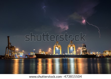 Container Cargo freight ship with working crane bridge in shipyard at dusk and lightning storm
	
