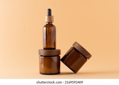 Container for cosmetics and creams. Glass brown jar with wooden lid. Bottle with pipette for oil Beige background. Monochrome concept. Place for a label. Cream jars. Beauty and care. Minimalism