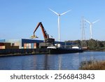 Container crane, containers and barge on the Kempisch Canal, Belgium. Industrial transport via waterway.