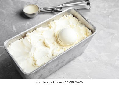 Container With Delicious Vanilla Ice Cream And Scoop On Table