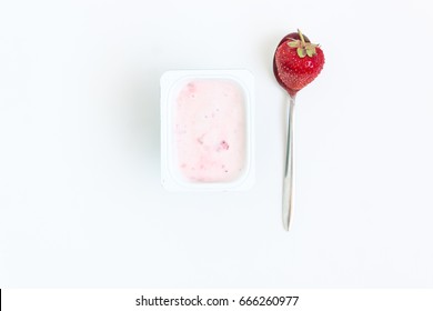 Container With Strawberry Yogurt And A Spoon With One Strawberry, Top View, Isolated On A White Background.