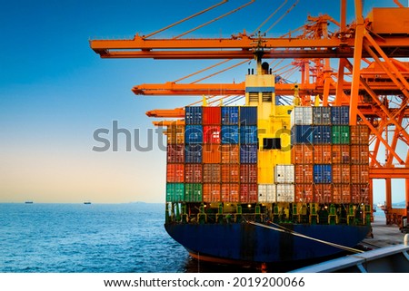 
Container terminal, container ship discharge cargo at port. Quay crane lift off container box load onto truck. Container port logistics operation.