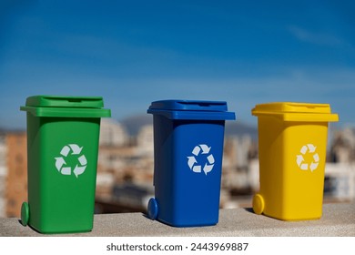 Container trash bin for recycling with city background. Yellow, green, blue bins for recycle plastic, paper and glass trash. Environmental awareness, recycling, waste management concept