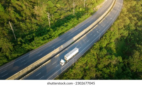 Container Truck with Cargo Trailer Drives on High way the Road aroud mountain forest. Green Cargo Truck on the road in green forest. Concept ecological green transportation 