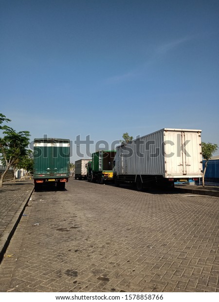 Container trucks are\
parked by the road during the day \